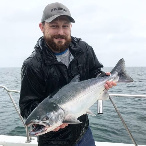 A man holding a silver (coho) salmon