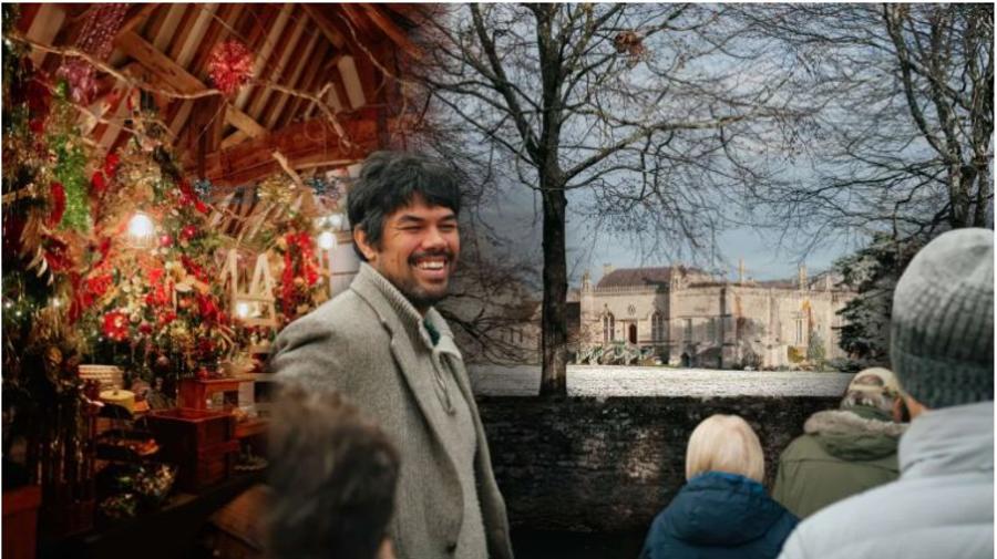 Guide from In & Beyond Bath in the Cotswolds leading a group outdoors beside festive decorations, with a snow-covered historic-looking building visible in the distance.