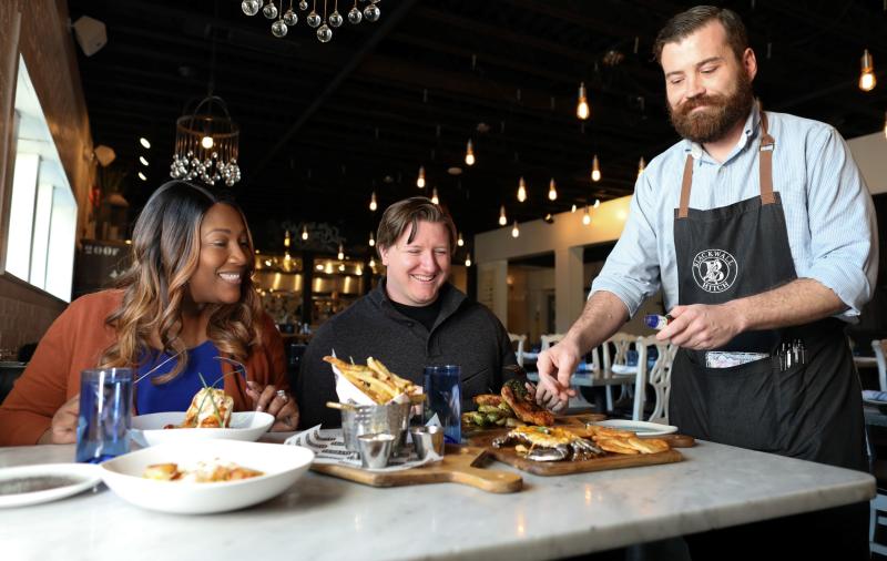 Annapolis restaurant Week image of couple sitting at a table with server placing food on the table