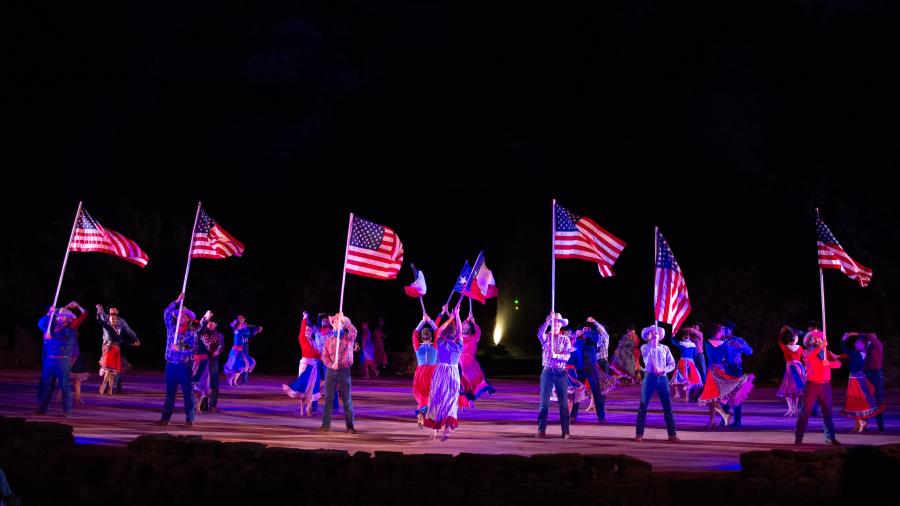 Actors on holding texas flags on stage