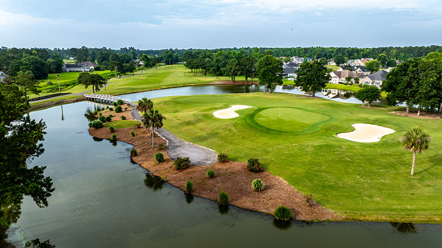 an aerial view of a golf course green surrounded by a water trap on 3 sides at Brunswick Plantation