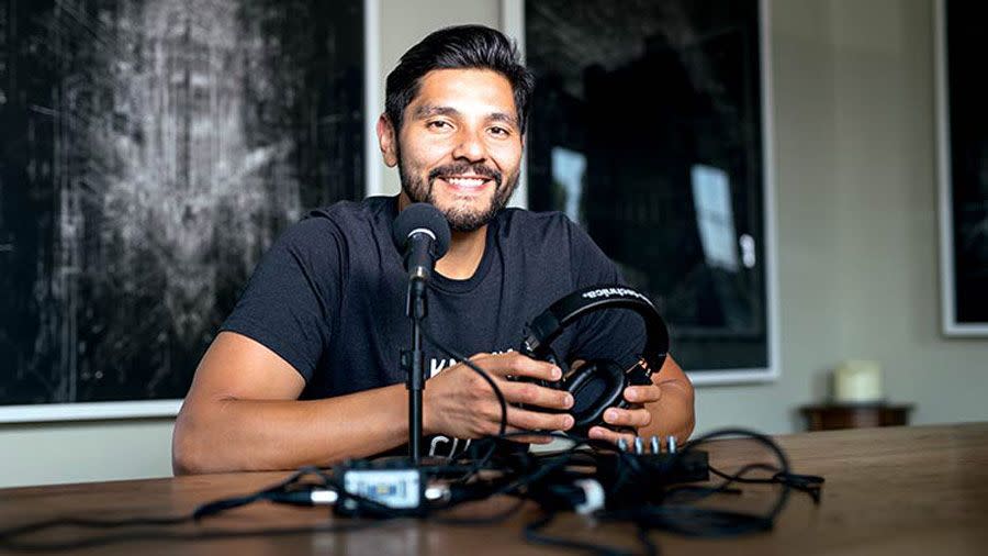 Fabian Rodriguez - sitting at a table in a recording studio smiling with headphones in his hands