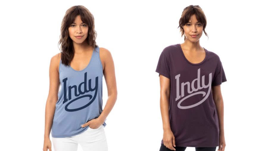 Two women wearing Indy-branded tees. One wearing blue tank and other wearing purple shirt. 