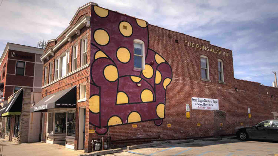 Red armchair with yellow polka dots on the side of a building in Broad Ripple