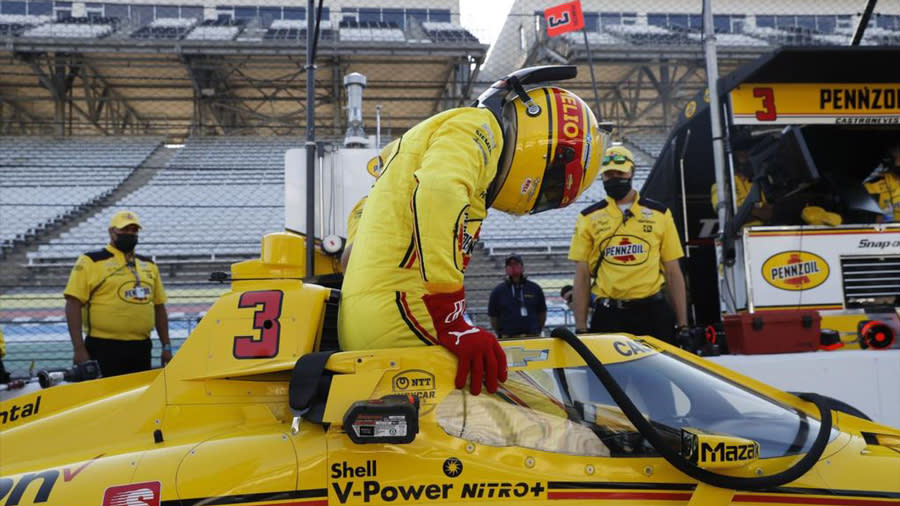 Helio Castroneves standing next to an IndyCar