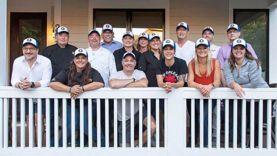 Team Indiana with hats on a porch. About 12 people.