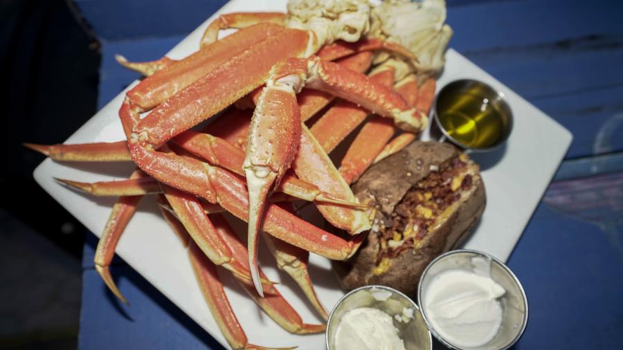 Several snow crabs with a loaded baked potato, with sides of drawn butter, whipped butter and sour cream