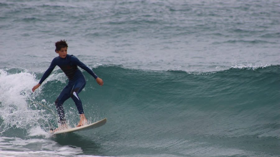 An adolescent wearing a wet suit, surfboarding in Pompano Beach