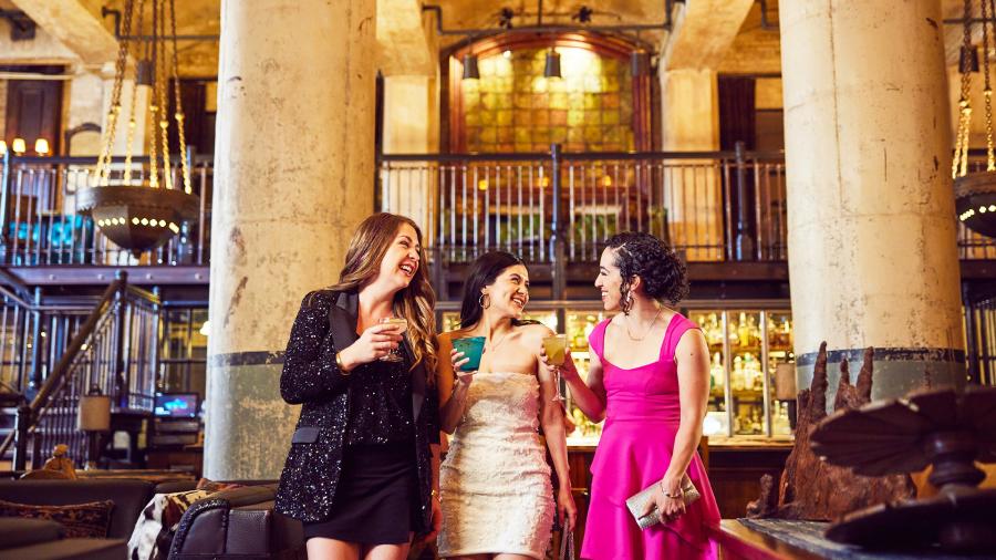 Three girls enjoying drinks in beautiful room with two large pillars