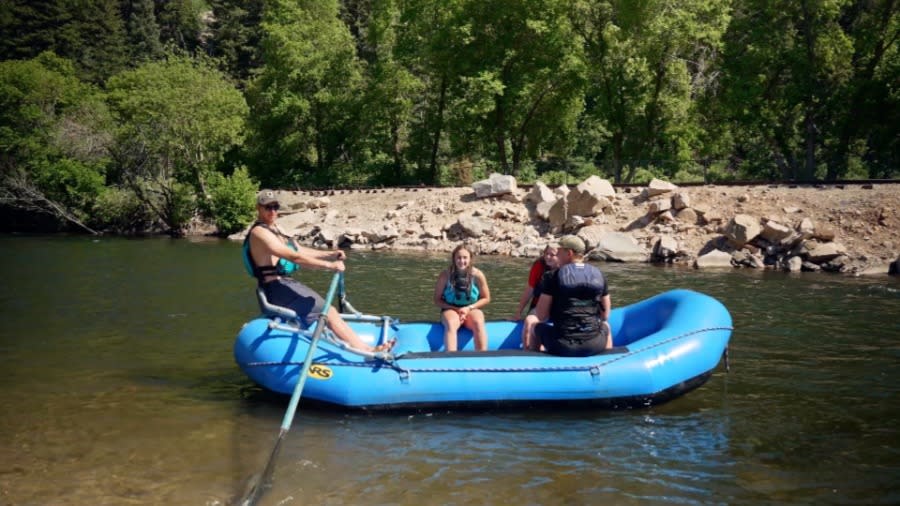 4 riders on a blue raft floating the Provo River