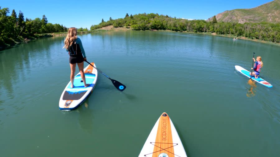 two paddle boarders and three boards on maple lake