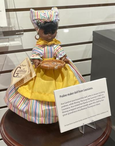 Doll Ava purchased in Louisiana wearing a dress with yellow apron and holding platter of pralines
