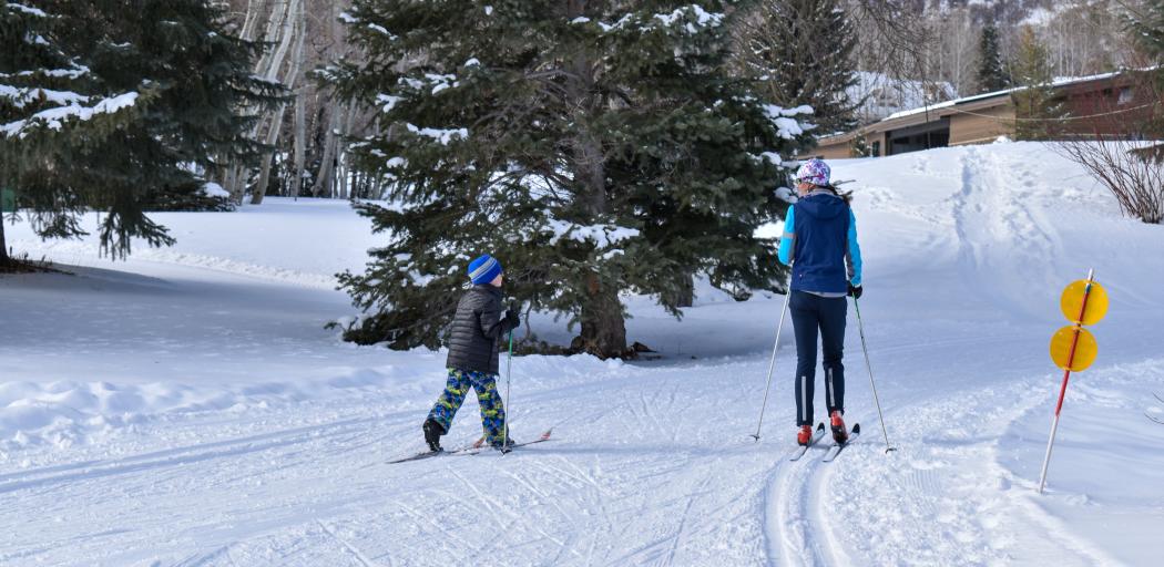 Young boy learning how to nordic ski with instructor