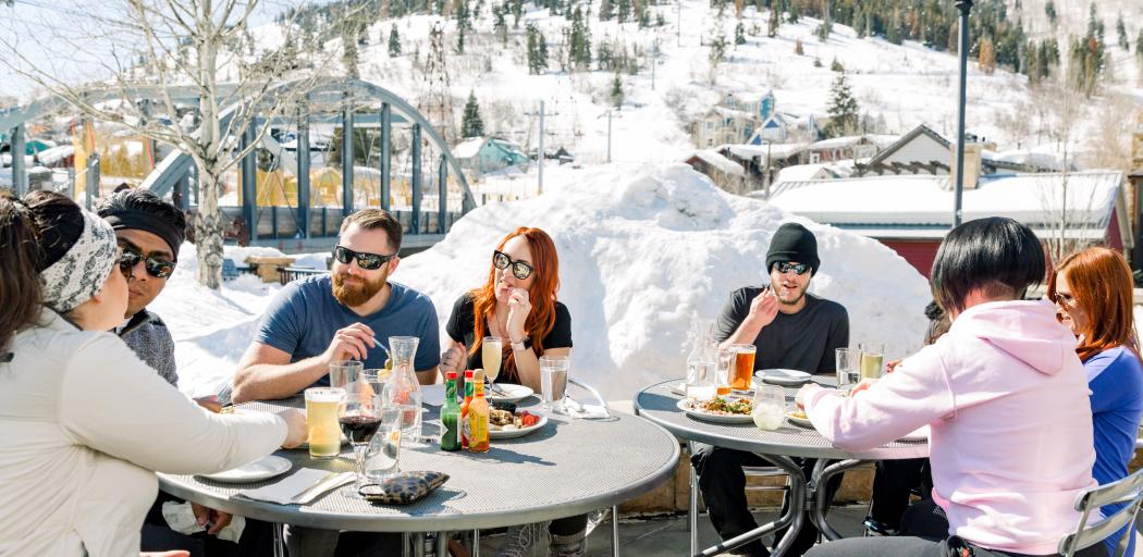 Group of friends eating at bridge on the patio on a spring day apres ski
