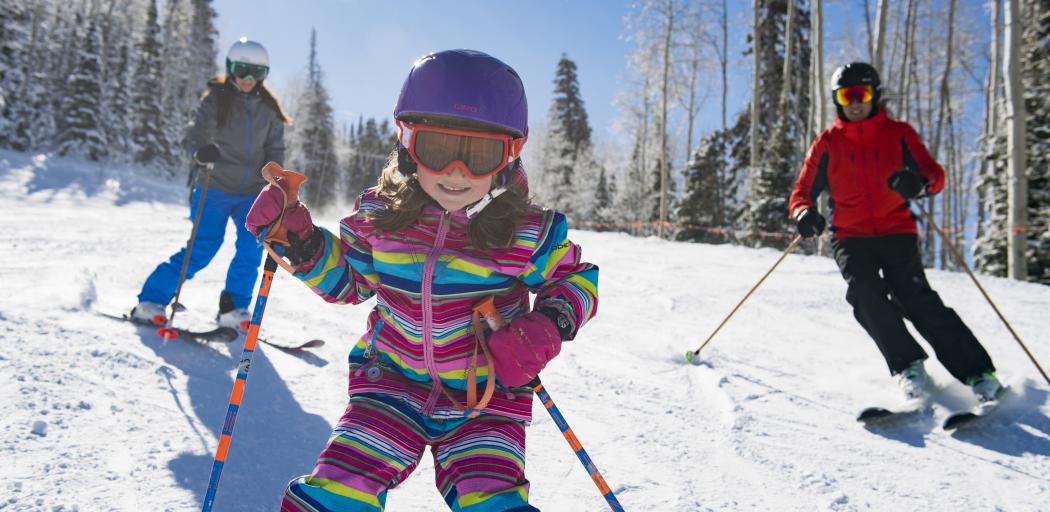 Young girl skiing with her parents