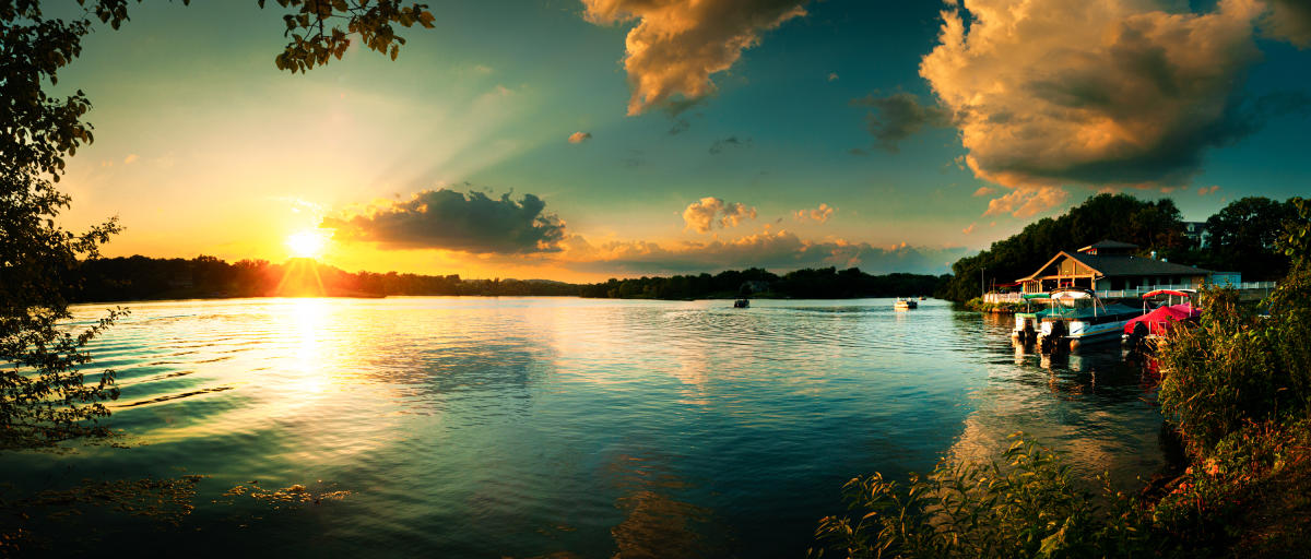 Sunset over a lake, with boats and a dock in the foreground.