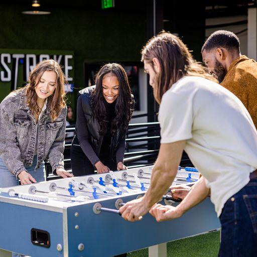 Two couples play air hockey at PopStroke
