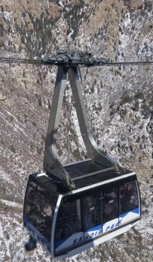 An image of a Sandia Peak Aerial Tramway tram car passing by the window of the other tram car