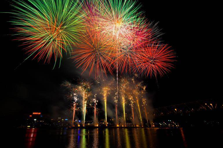 Towers of yellow fireworks under four blooming red, green and yellow explosions of Rozzi's fireworks over the Ohio river