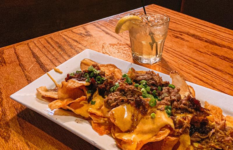 A plate of nachos and a cocktail from Crazy Horse