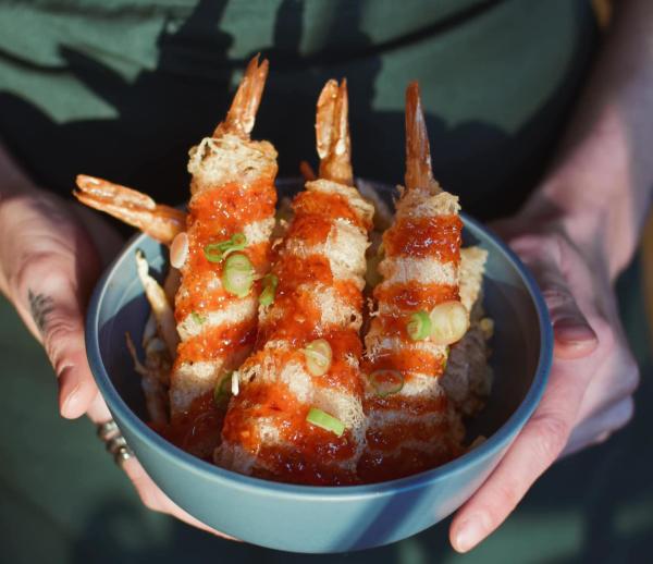 A server holding a bowl of the Firecracker Shrimp from Understory Columbus