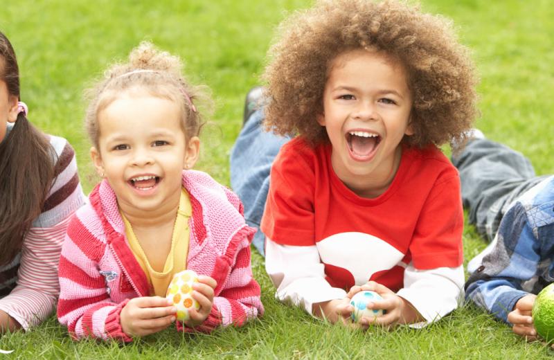 Children laid on grass with Easter eggs. Click to read more about things to do for Easter in Staffordshire.