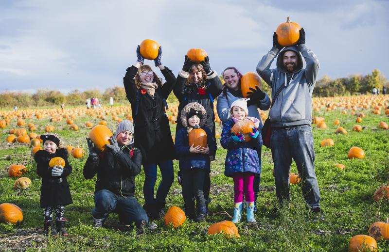 family with their pumpkin haul in the patch