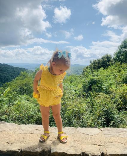 A toddler stands on a low stone wall at an overlook in Monte Sano State Park.