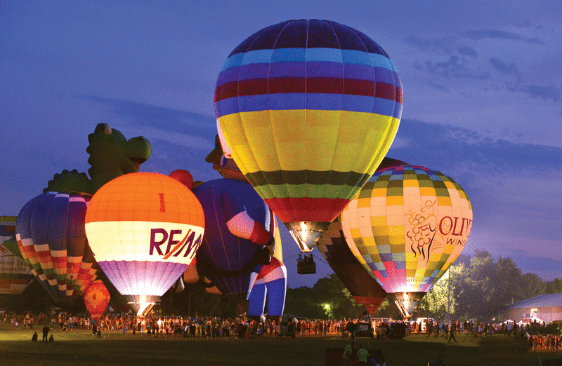 Several hot air balloons taking off at dusk at the Indiana Balloon Festival
