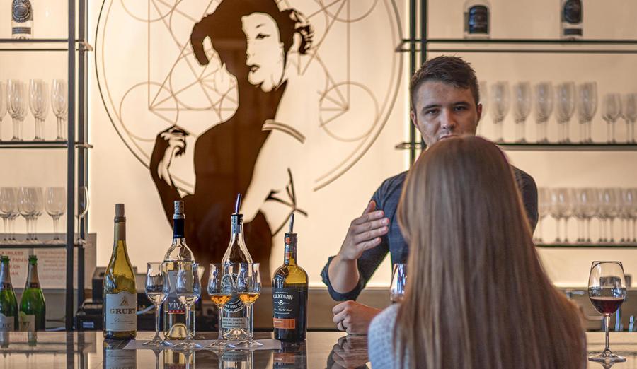 A man speaks to a woman next to a selection of wine from Crafted
