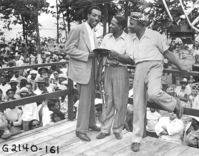 Carr's Beach, Hoppy Adams and two men stand on the grandstand.