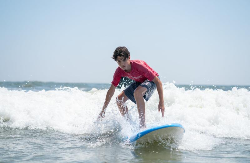 A kid riding a wave on a surfboard 
