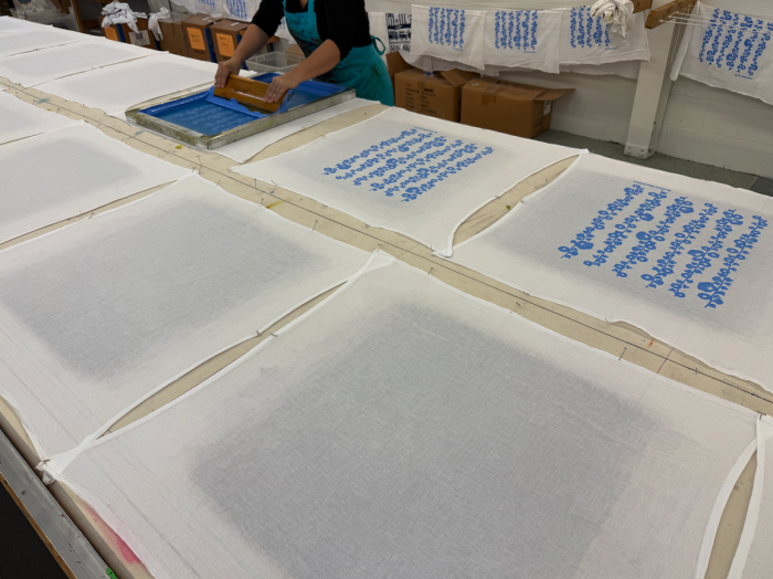 A Kei and Molly employee screen prints some flour sack dish towels.