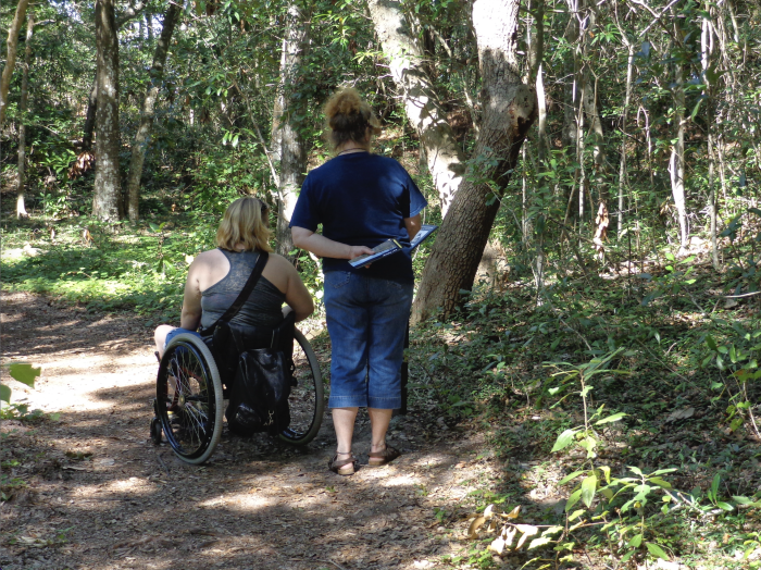 A wheelchair user travels along a wooded path at the Fort Raleigh National Historic Site.