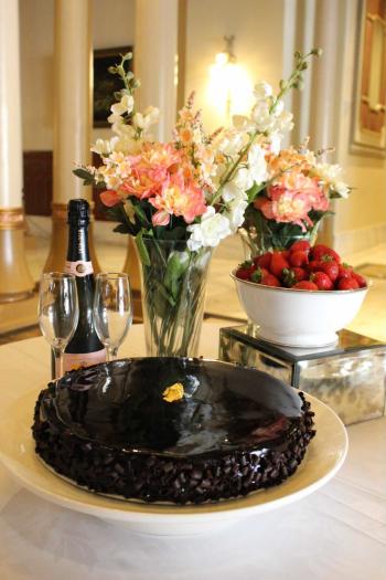 Chocolate cake from 1886 Bakery & Cafe in front of a bowl of strawberries, a bottle of champagne and two champagne glasses