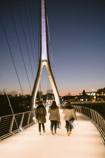Three girls walking on the Dublin Link pedestrian bridge at night