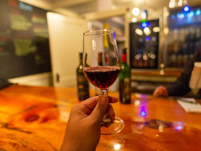 A Glass of Red Wine being held up to the camera at La Di Da Wine Bar in Clayton