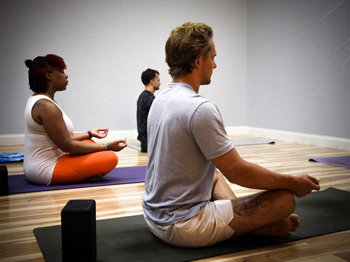 Three people meditating in a yoga class.