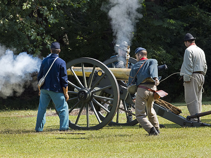 Four men dressed in Civil War period costumes fire a cannon at Bentonville Battlefield.