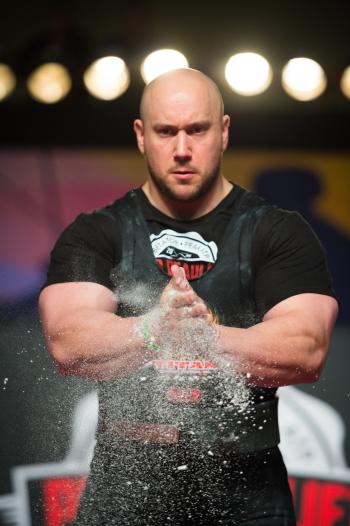 Muscular weight lifter applying chalk to hands at Arnold Sports Festival