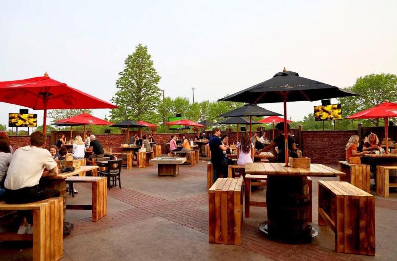 Red and black square umbrellas cover diners on the patio at Brick & Bourbon