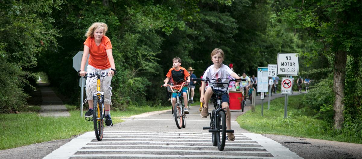 Young people ride bicycles on the Tammany Trace hike/bike path through Abita Springs, June 2018.