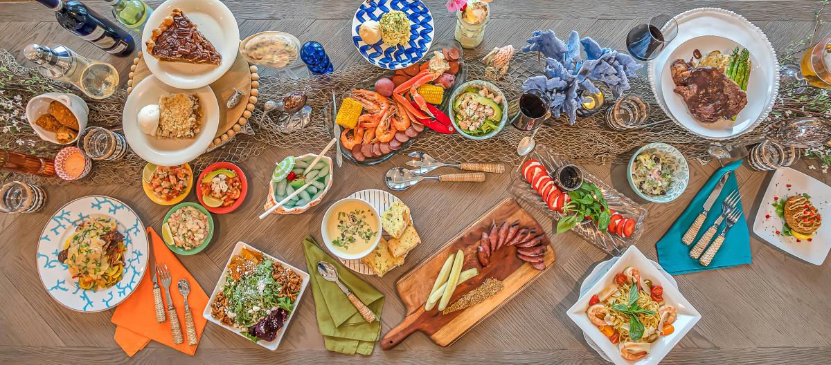 Overhead shot of a long dining table filled with dishes from salads to soups to steaks and desserts