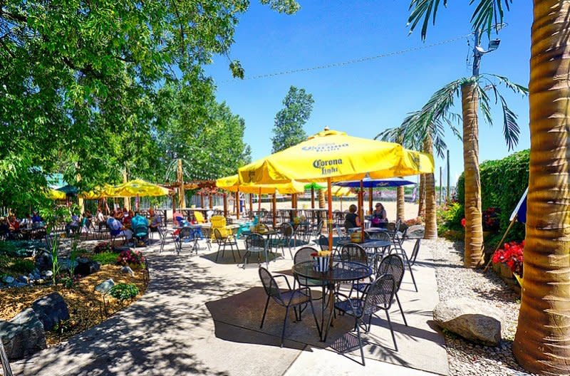 Round yellow umbrellas mark the full tables on the three-lined patio at The Lookout Bar & Grill