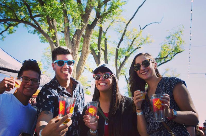 Four people smile at the camera holding glasses of beer.