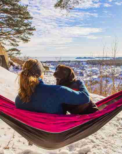 Woman and dog in a hammock, with a view in wintertime