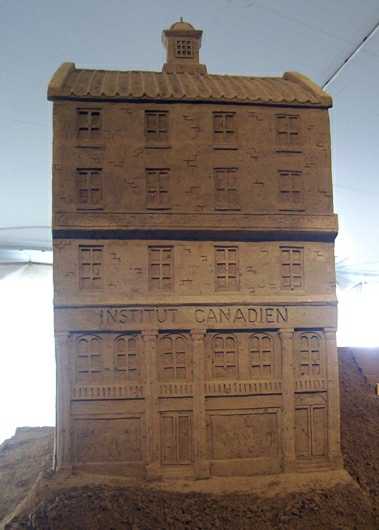 Sand sculpture of a tall skinny storefront building