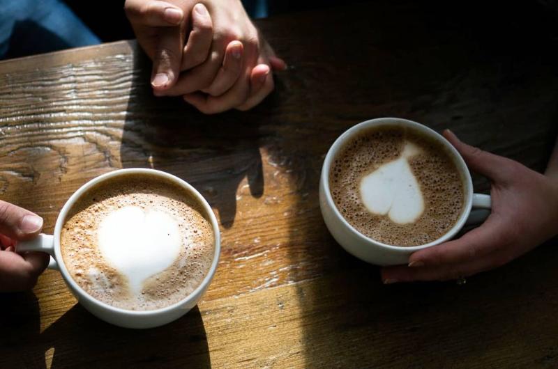 Two people holding hands and lattes