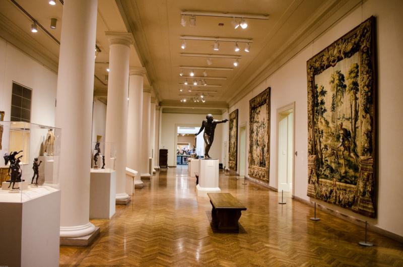A sculpture of a man pointing stands in the middle of a gallery hall at the Minneapolis Institute of Art