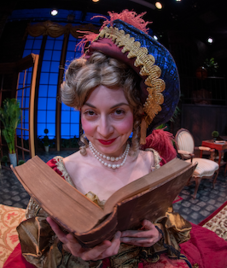 A woman peers up from a book dressed in period garb